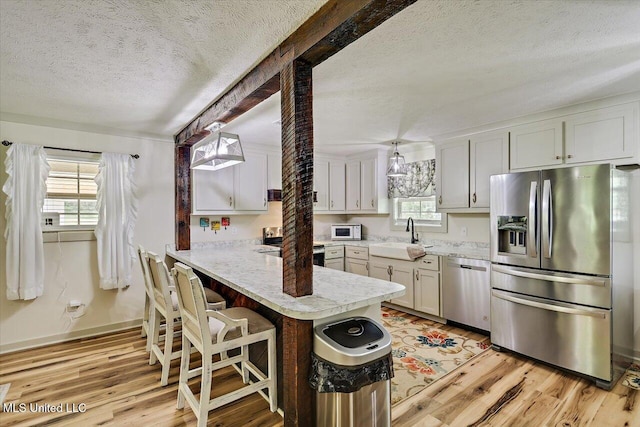 3341 Simpson Highway 13, Mendenhall, MS 39114 - kitchen with stainless steel appliances, a sink, a textured ceiling, a peninsula, and light wood-type flooring