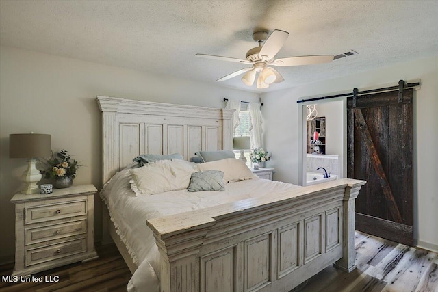 3341 Simpson Highway 13, Mendenhall, MS 39114 - bedroom featuring dark wood-type flooring, a textured ceiling, a barn door, and a ceiling fan