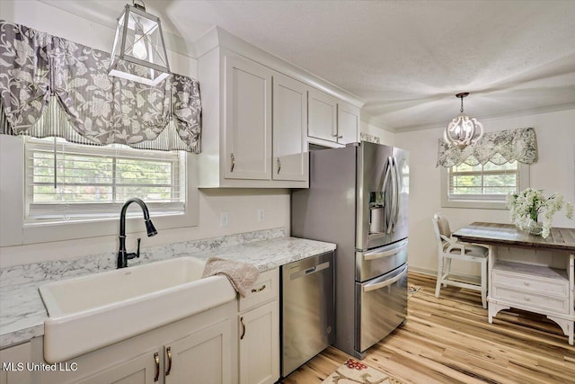 3341 Simpson Highway 13, Mendenhall, MS 39114 - kitchen featuring appliances with stainless steel finishes, a sink, light wood-type flooring, hanging light fixtures, and a textured ceiling