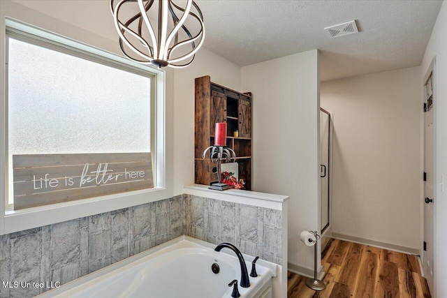 3341 Simpson Highway 13, Mendenhall, MS 39114 - bathroom featuring a garden tub, wood finished floors, a shower stall, a chandelier, and a textured ceiling