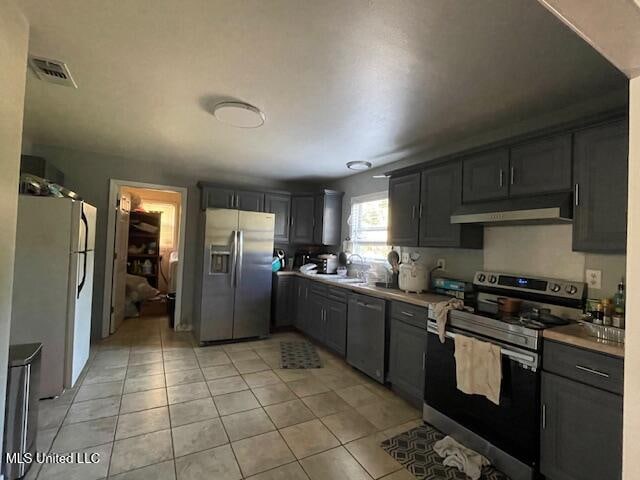 kitchen with sink, stainless steel appliances, and light tile patterned floors