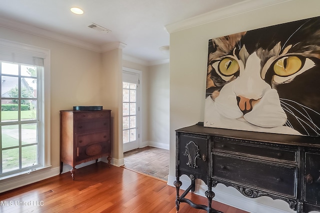 interior space with a wealth of natural light, crown molding, and wood-type flooring