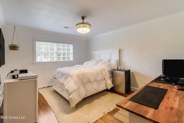 bedroom featuring ornamental molding and hardwood / wood-style floors