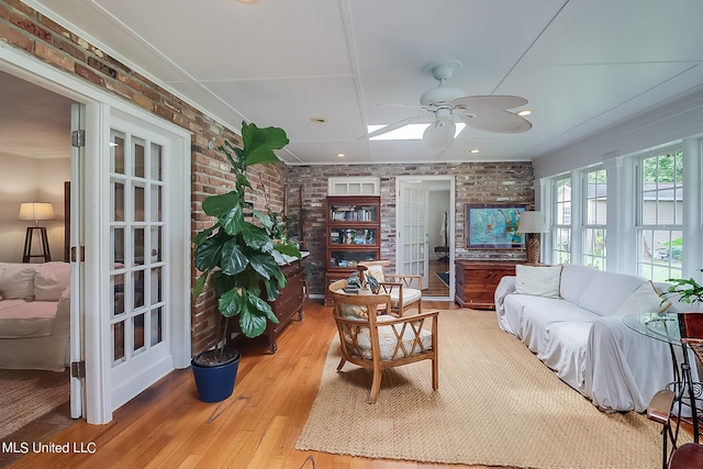 living room with brick wall, wood-type flooring, and ceiling fan