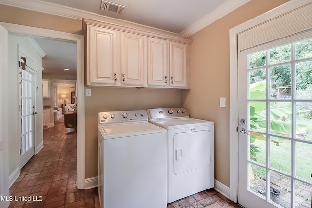 clothes washing area featuring crown molding, washing machine and dryer, and cabinets