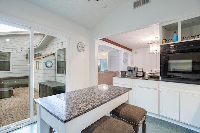 204 Trautman Ave, Long Beach, MS 39560 - kitchen featuring lofted ceiling, black oven, dark tile patterned flooring, dark stone counters, and white cabinetry