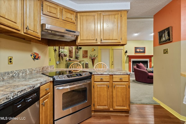 2804 Oakridge Cir, Gulfport, MS 39507 - kitchen with appliances with stainless steel finishes, under cabinet range hood, light countertops, dark wood finished floors, and a fireplace