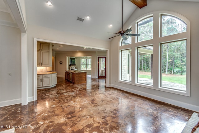 unfurnished living room featuring ceiling fan, a healthy amount of sunlight, high vaulted ceiling, and beam ceiling