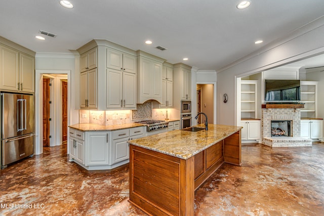 kitchen featuring an island with sink, crown molding, light stone counters, and appliances with stainless steel finishes