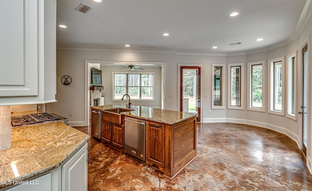 kitchen featuring a kitchen island with sink, light stone counters, a healthy amount of sunlight, and sink