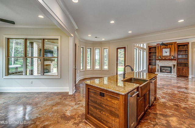 kitchen featuring a wealth of natural light, sink, an island with sink, and a fireplace