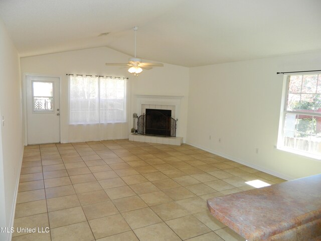 unfurnished living room featuring vaulted ceiling, ceiling fan, light tile patterned floors, and a tiled fireplace