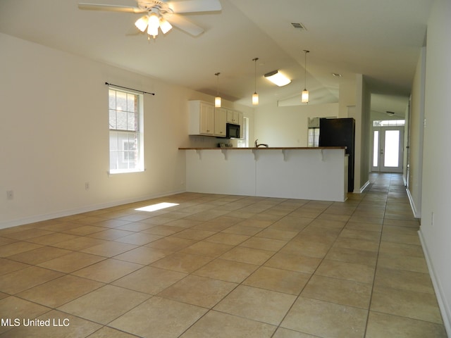 kitchen featuring light tile patterned flooring, a peninsula, a kitchen breakfast bar, open floor plan, and black appliances