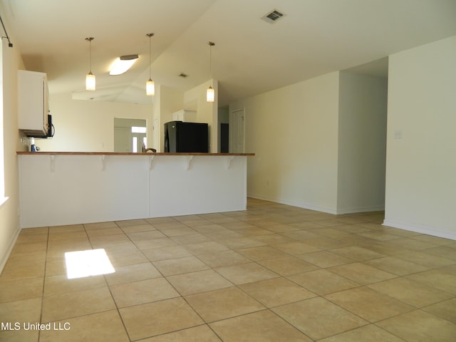 unfurnished room with lofted ceiling, visible vents, baseboards, and light tile patterned floors