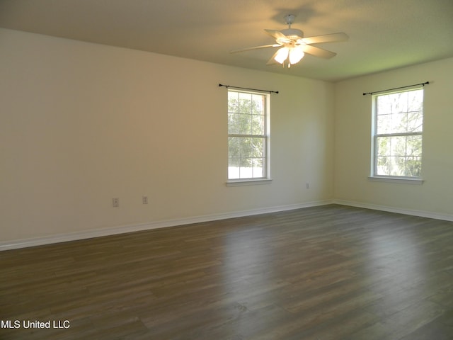 empty room with dark wood-style flooring, a healthy amount of sunlight, and baseboards