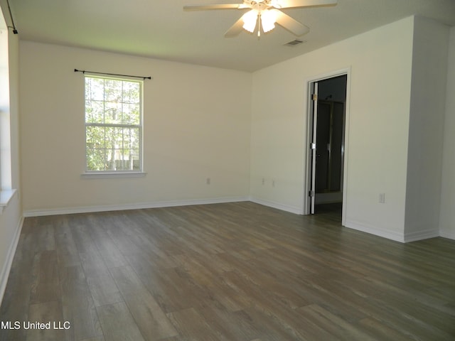 spare room featuring ceiling fan, dark wood-style flooring, visible vents, and baseboards