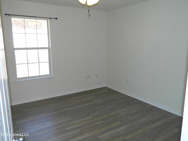 unfurnished room featuring dark wood-type flooring, a wealth of natural light, and baseboards