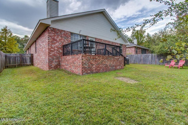 exterior space with a yard, a fenced backyard, a chimney, and brick siding