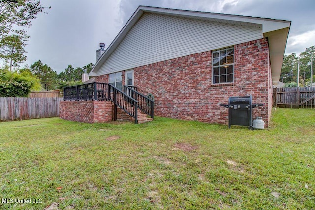 view of home's exterior featuring brick siding, a lawn, a fenced backyard, and stairs