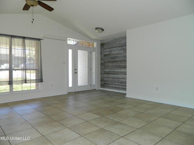 interior space with baseboards, vaulted ceiling, a ceiling fan, and light tile patterned flooring