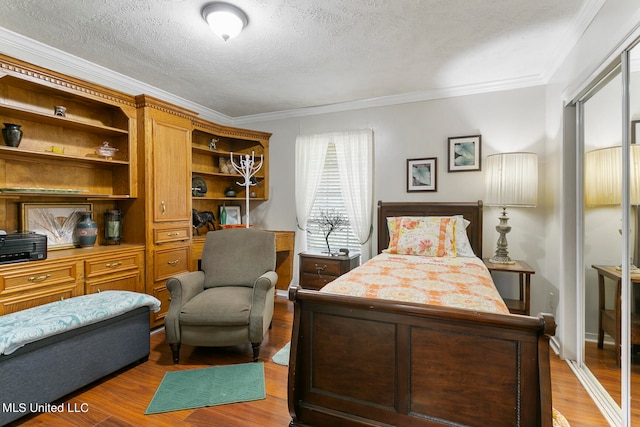 bedroom with ornamental molding, light hardwood / wood-style flooring, and a textured ceiling