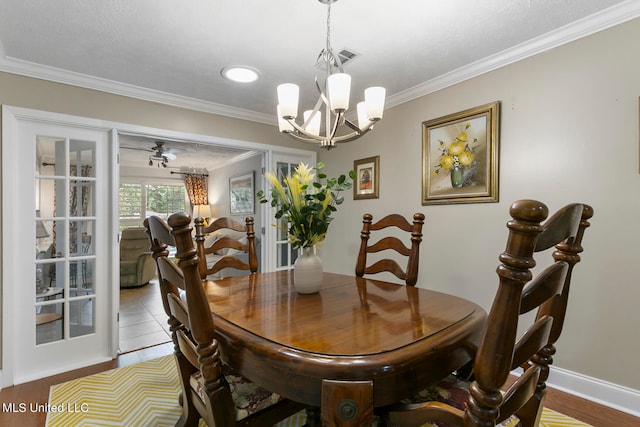 dining space with crown molding, ceiling fan with notable chandelier, and tile patterned flooring