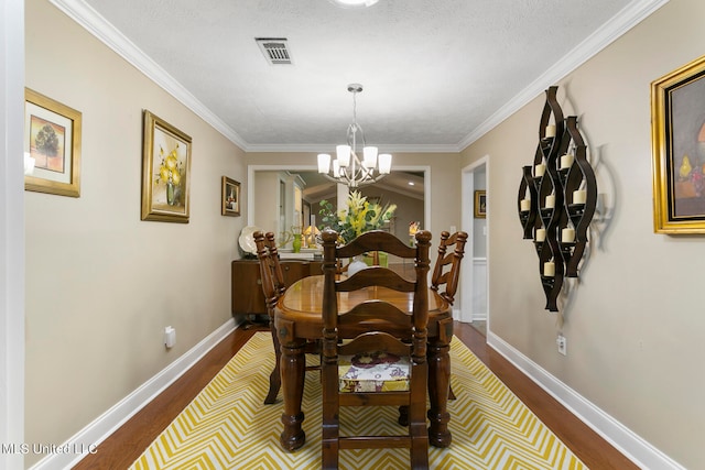 dining space with ornamental molding, hardwood / wood-style floors, a chandelier, and a textured ceiling