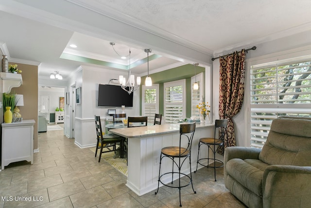 kitchen featuring hanging light fixtures, kitchen peninsula, a tray ceiling, a breakfast bar, and crown molding