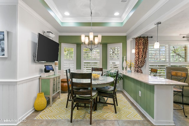 tiled dining room featuring a notable chandelier, ornamental molding, and a raised ceiling