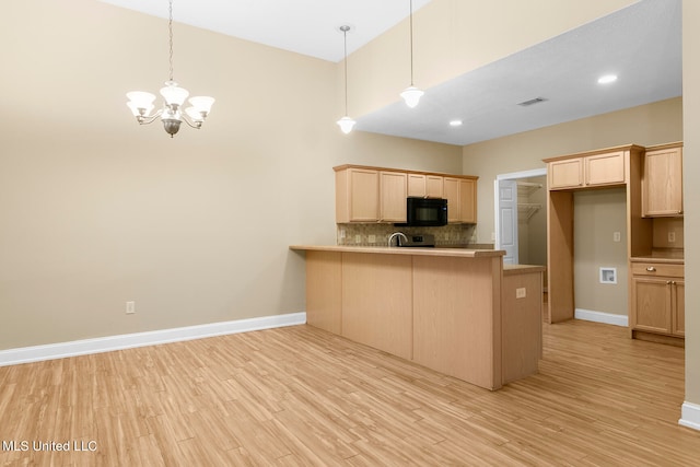 kitchen with light hardwood / wood-style floors, light brown cabinetry, decorative light fixtures, and kitchen peninsula