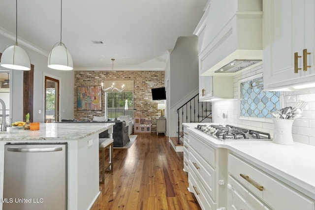 133 Saddlebrook Cv, Madison, MS 39110 - kitchen featuring stainless steel appliances, white cabinetry, visible vents, custom exhaust hood, and brick wall