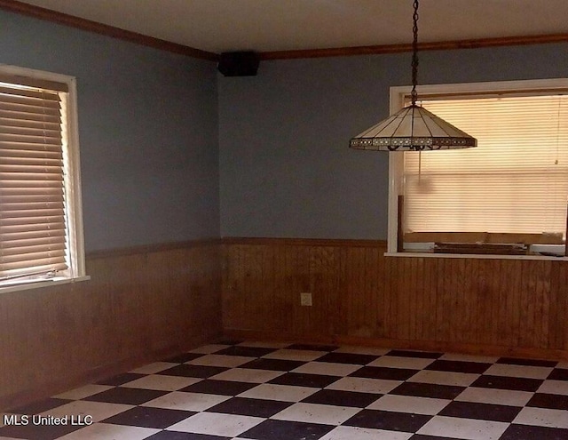 unfurnished dining area featuring wood walls and ornamental molding