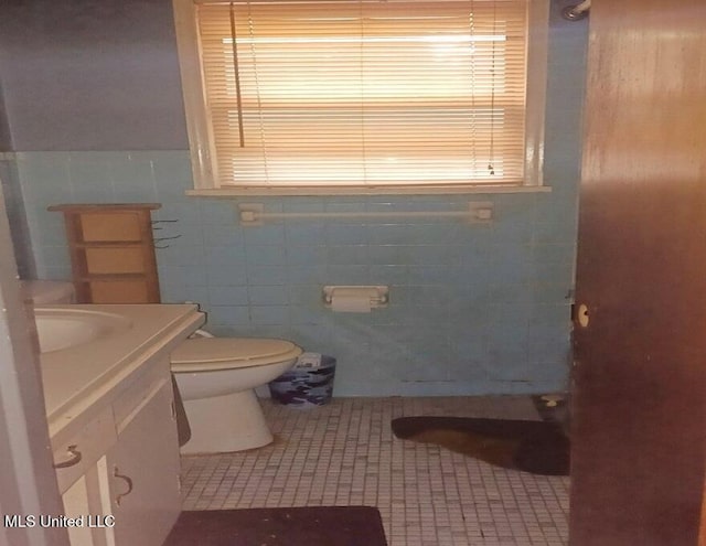 bathroom with tile patterned flooring, vanity, toilet, and tile walls