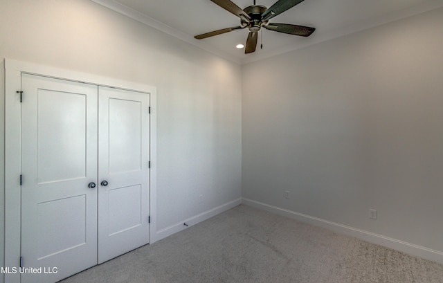 unfurnished bedroom featuring ceiling fan, crown molding, a closet, and carpet floors