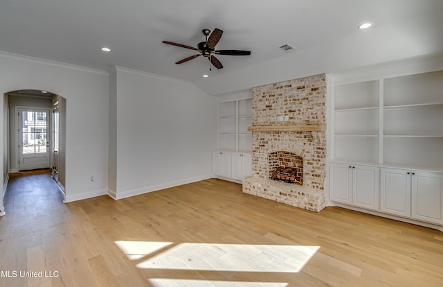 unfurnished living room with built in shelves, light wood-type flooring, a fireplace, and ornamental molding