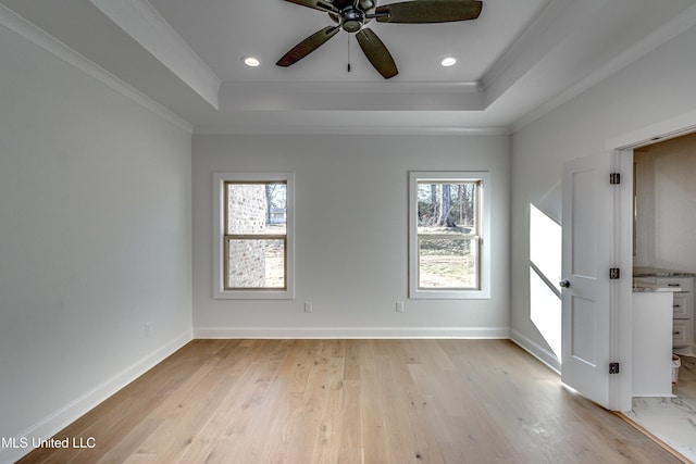 empty room featuring ceiling fan, crown molding, light hardwood / wood-style flooring, and a raised ceiling