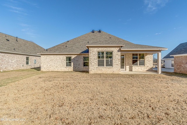 rear view of house featuring a lawn and a patio