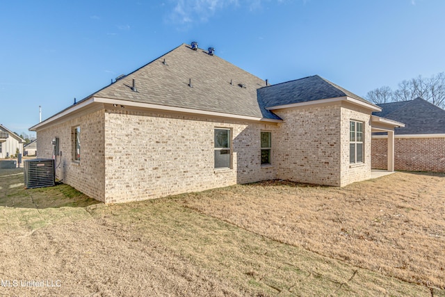 rear view of house with central AC unit and a yard