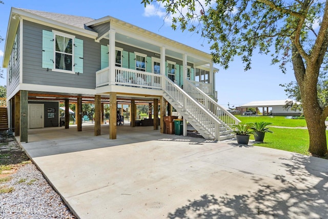 raised beach house with a front yard, covered porch, and a carport