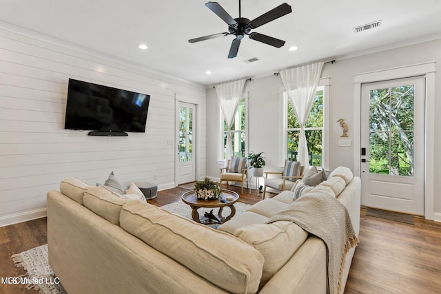 living room featuring ceiling fan, wood-type flooring, and wooden walls