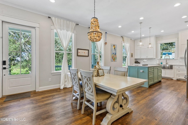 dining area with dark wood-type flooring, sink, and an inviting chandelier