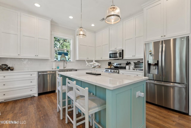 kitchen featuring white cabinetry, appliances with stainless steel finishes, hanging light fixtures, a center island, and dark hardwood / wood-style flooring