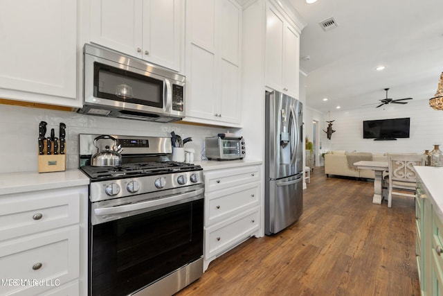 kitchen with dark hardwood / wood-style flooring, white cabinets, tasteful backsplash, ceiling fan, and appliances with stainless steel finishes