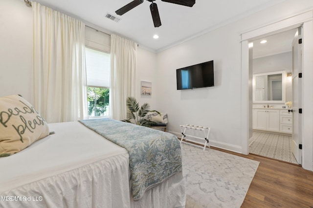 bedroom with dark hardwood / wood-style flooring, ensuite bath, sink, ornamental molding, and ceiling fan