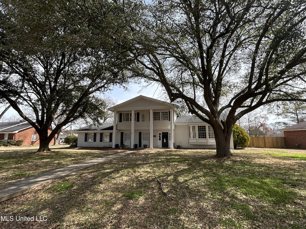 neoclassical / greek revival house featuring fence and a front yard