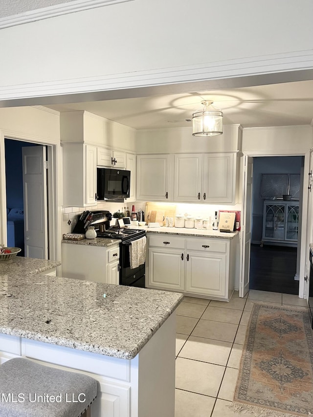 1202 Hemingway St, Greenwood, MS 38930 - kitchen with white cabinets, light tile patterned flooring, light stone counters, washer / clothes dryer, and black appliances