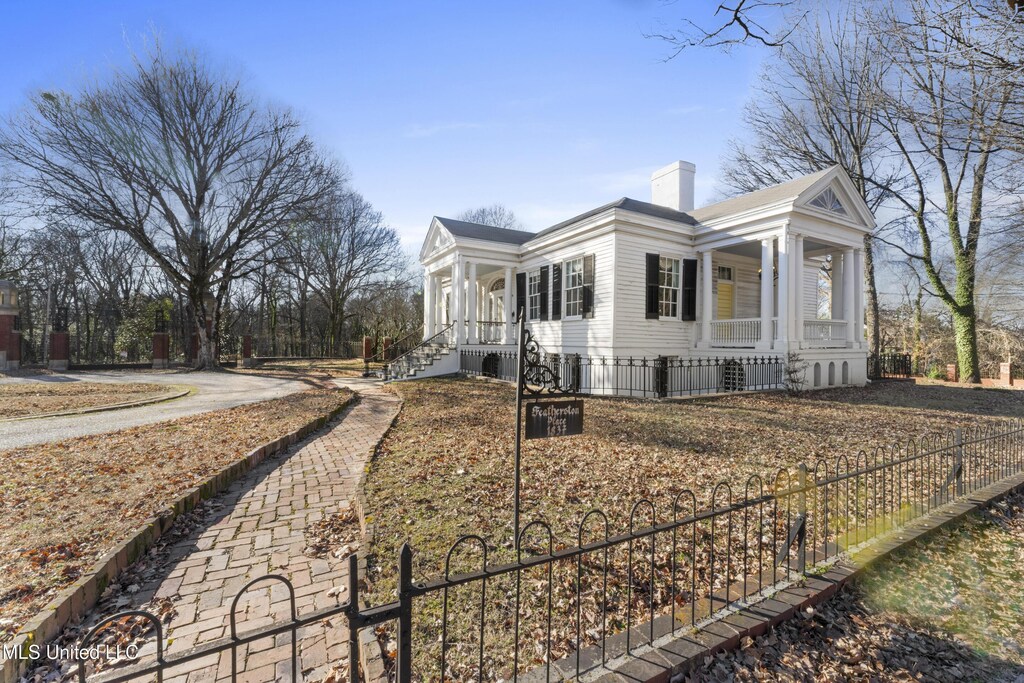 166 S Craft St, Holly Springs, MS 38635 - view of home's exterior with covered porch, a chimney, and fence