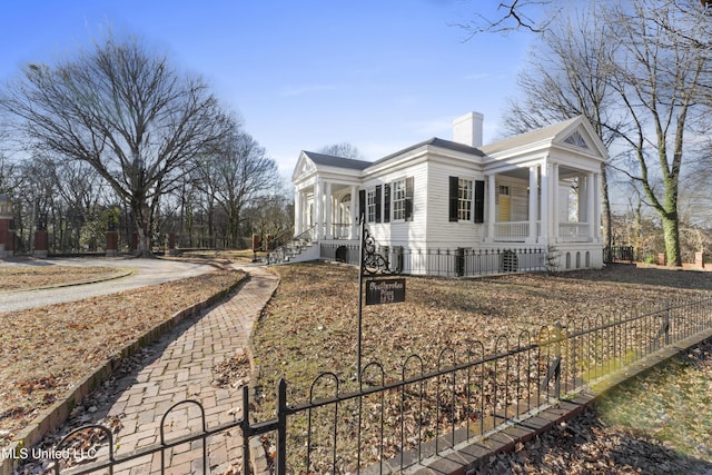 view of home's exterior with covered porch, a chimney, and fence