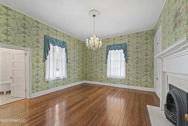 unfurnished living room with hardwood / wood-style flooring, baseboards, and wallpapered walls