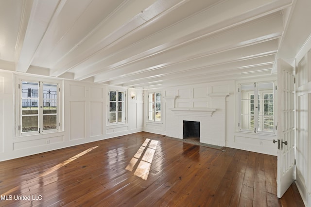 unfurnished living room featuring a fireplace, a decorative wall, hardwood / wood-style floors, and beamed ceiling